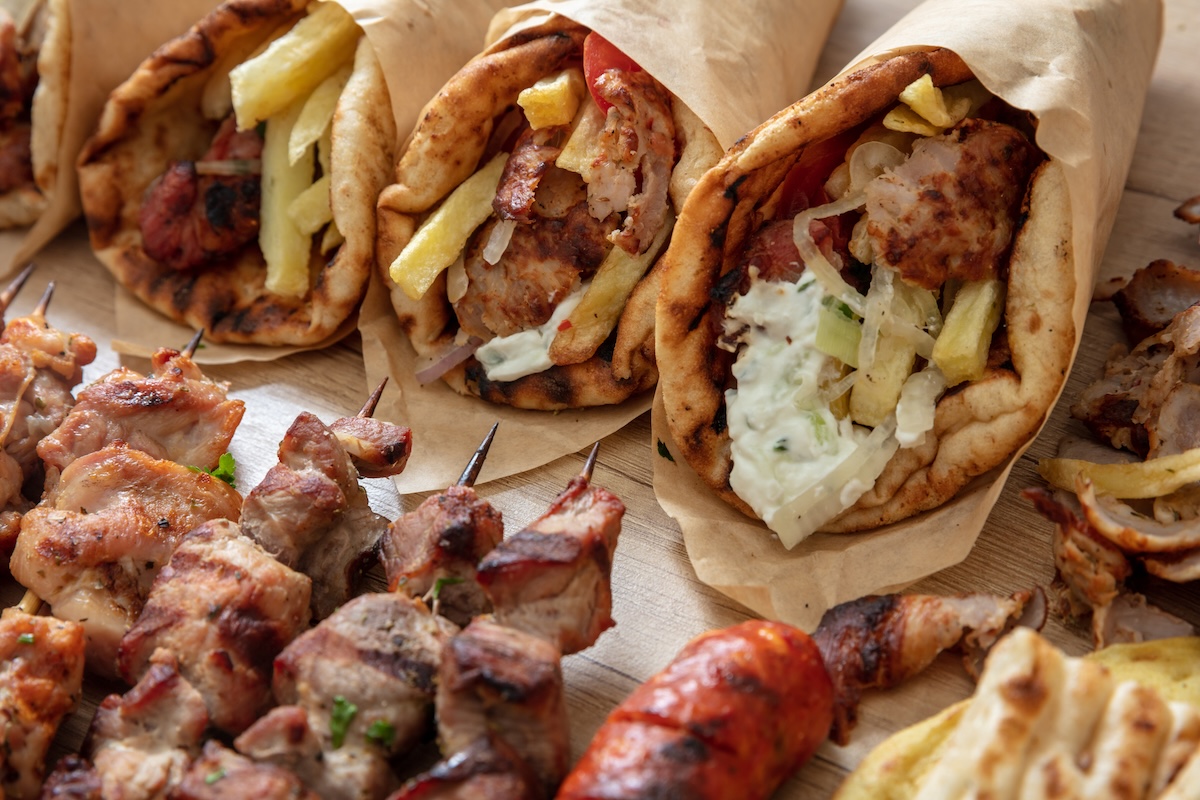 Greek traditional street food, gyro sliced meat, souvlaki skewer. Pita bread, tzatziki yogurt, potato tomato and onion on wooden table, top view